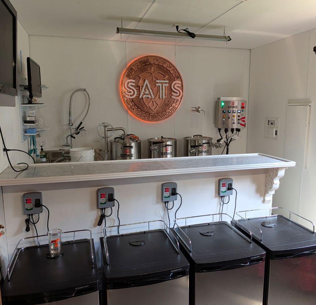 Inside the satsbrew brewery: the lit SATS sign above the brew kettles, with fermentation fridges below
